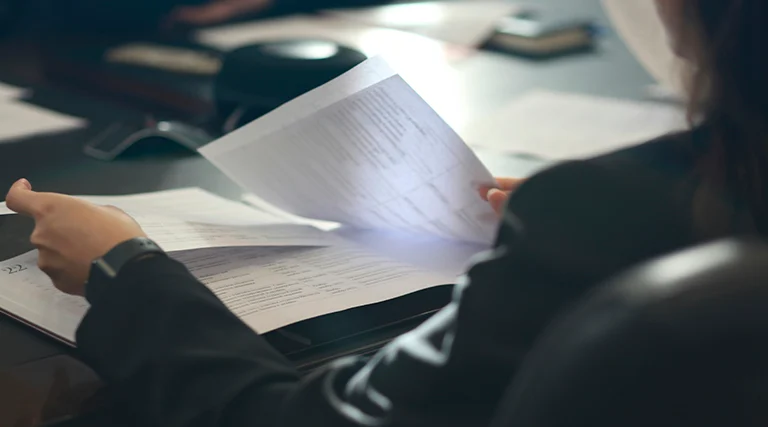 Pessoa analisando documentos e papéis em reunião representando documentos necessários para compra de imóvel usado