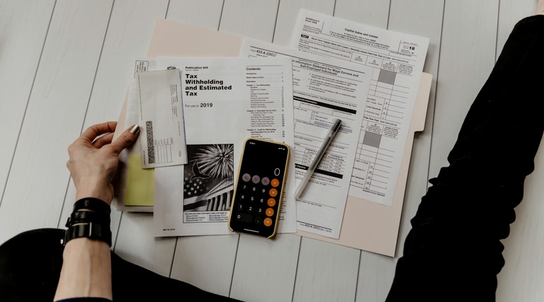 Pessoa organiza documentos fiscais e calculadora sobre mesa para análise de venda de imóvel não registrado