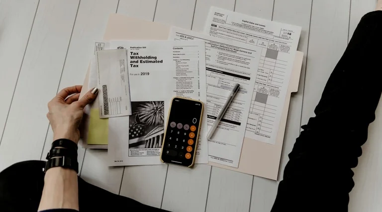 Pessoa organiza documentos fiscais e calculadora sobre mesa para análise de venda de imóvel não registrado