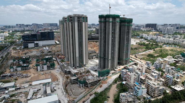 Prédios residenciais em construção cercados por área urbana com diferentes tipos de imóveis ao redor