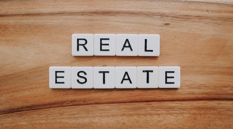 Advogado para Compra de Imovel de Alto Valor: blocos de letras formando as palavras Real Estate sobre superficie de madeira