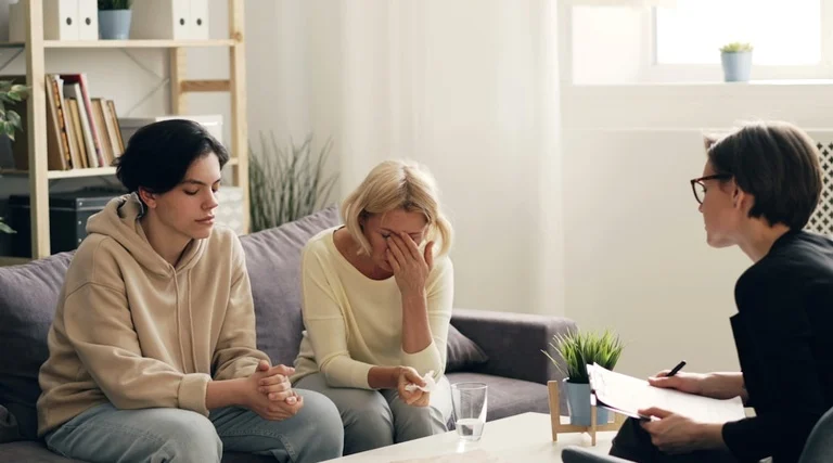 Advogado para Compra de Imóvel de Alto Valor em Reunião Advogado para Compra de Imóvel de Alto Valor: profissional de óculos segurando documento conversa com duas mulheres sentadas