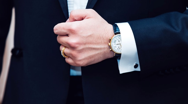 Advogado para Compra de Imóvel de Alto Valor: mãos masculinas com terno escuro, relógio de luxo e abotoaduras