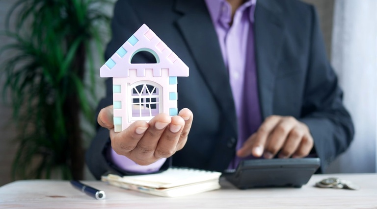 Posso Comprar Imóvel e Fazer Escritura no Nome dos Filhos: Profissional segura miniatura de casa representando decisão