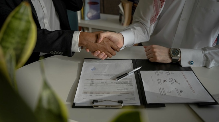 Quanto Custa Advogado Para Compra de Imóvel: Aperto de mãos entre profissionais durante assinatura de contrato de compra