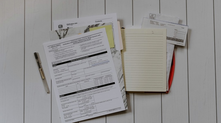 riscos de comprar imovel em inventario: Documentos de inventário espalhados sobre mesa com bloco de notas e caneta