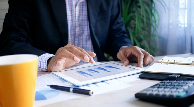 ITBI cobrado a mais na compra do imóvel: análise ITBI cobrado a mais na compra do imóvel: Profissional analisa gráficos financeiros e documentos sobre mesa com calculadora