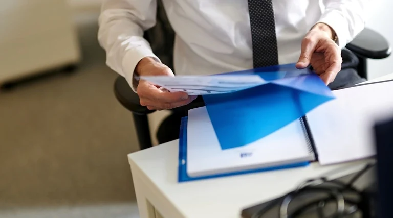 ITBI cobrado a mais na compra do imóvel: ITBI cobrado ITBI cobrado a mais na compra do imóvel: Profissional entrega pasta azul com documentos durante análise de processo