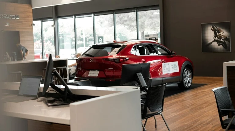 Carro usado exposto em loja automotiva Carro usado com defeito comprado na loja: veículo vermelho exposto em showroom com mesas e cadeiras ao redor