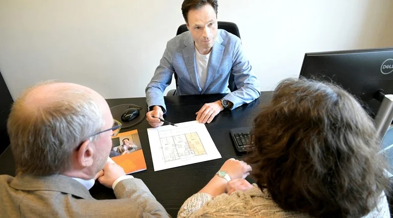 Consultor explica condições de contrato a casal durante atendimento sobre desistência da compra de carro financiado