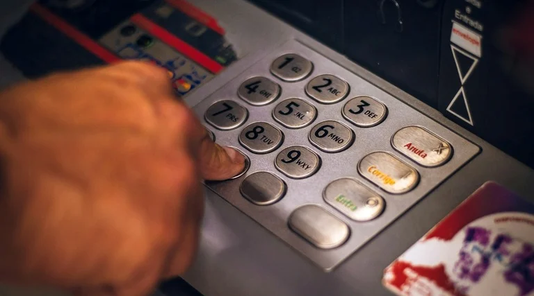 Golpe da falsa central bancária em caixa eletrônico Golpe da falsa central bancária: mão digitando senha em teclado numérico de caixa eletrônico